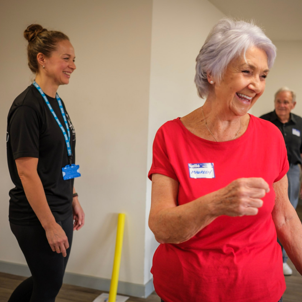 An older woman smiling happily at an exercise class with the instructor in the background